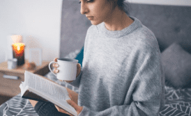 Mulher lendo um livro com um café na mão